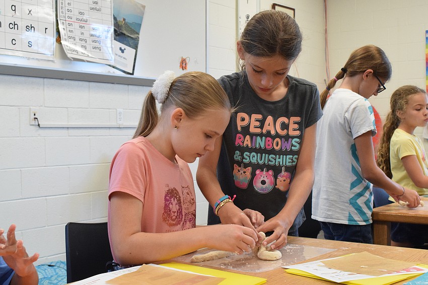 Ally Hagan, who is 10, works with Marin Summerlee, who is 10, to make a pretzel. While some campers made traditional pretzels, others opted to make pretzel bites.