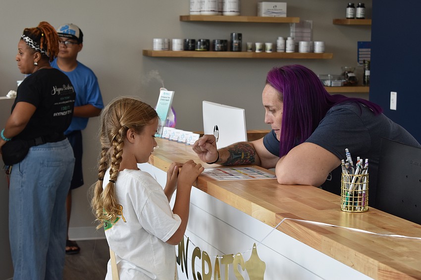 Sarasota 7-year-old Zoe Weaver is greeted by Pinnacle Chiropractic employee Bethany Kopacz during the grand opening.