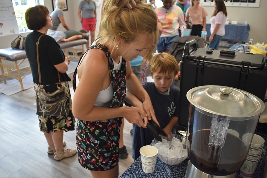 Danille Gilmore and her 8-year-old son Hayden Gilmore gather refreshments at the Pinnacle grand opening.