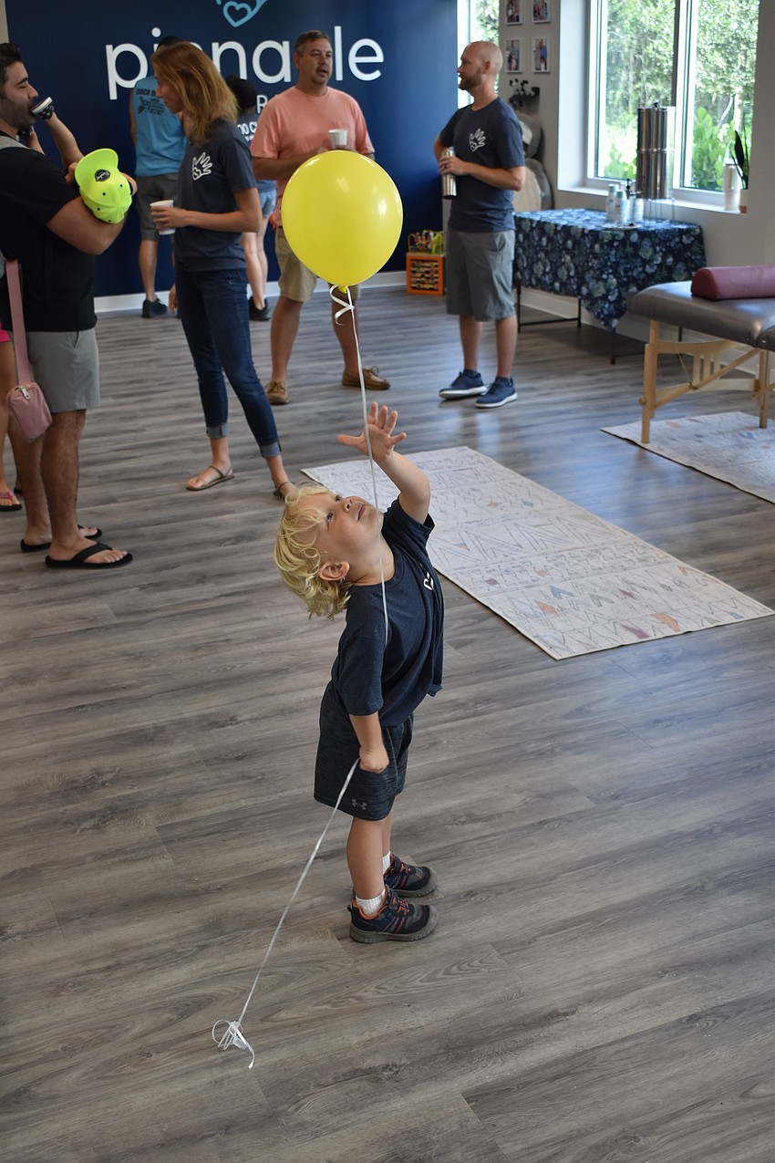 Perry Hallam, 2, entertains himself with a balloon during the grand opening.