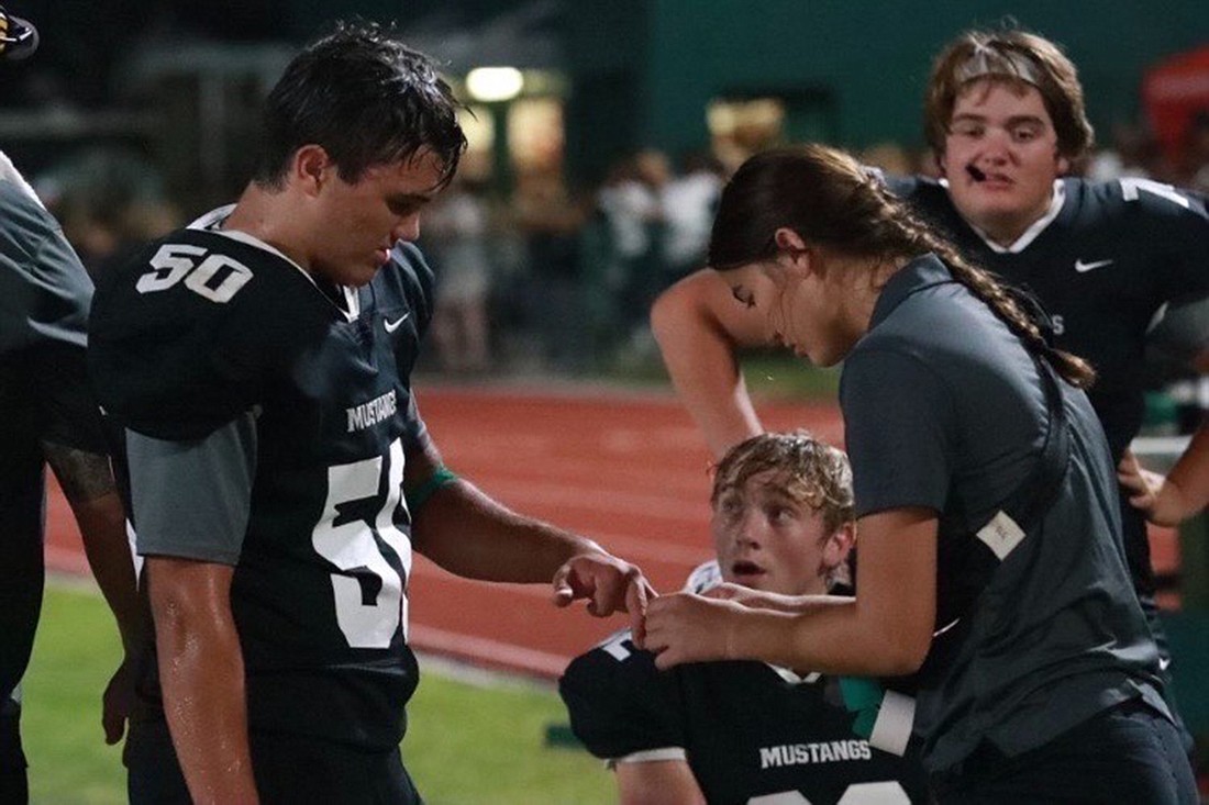 Reagan Gross, here taping up the hand of Mustangs linebacker Brooks Moyer, was a part of the Lakewood Ranch athletic training program for two years. (Courtesy photo)