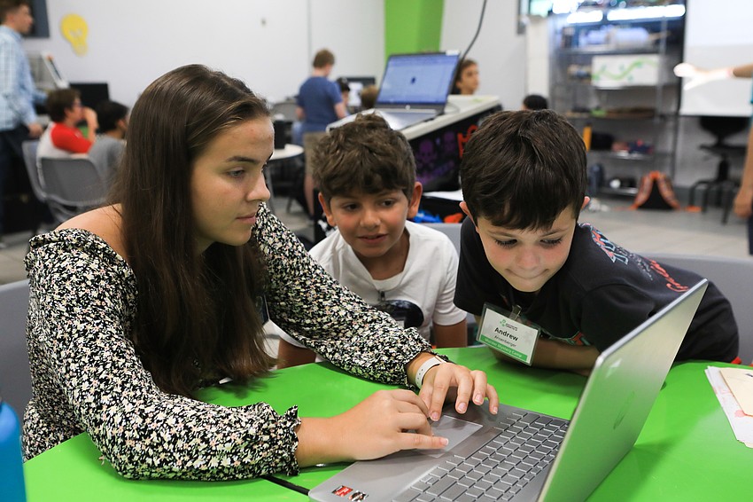 Volunteer Sophia Teijelo teaches Ramzi Ghamra and Andrew Ansenberger how to make T-shirt designs they can wear to the wedding.