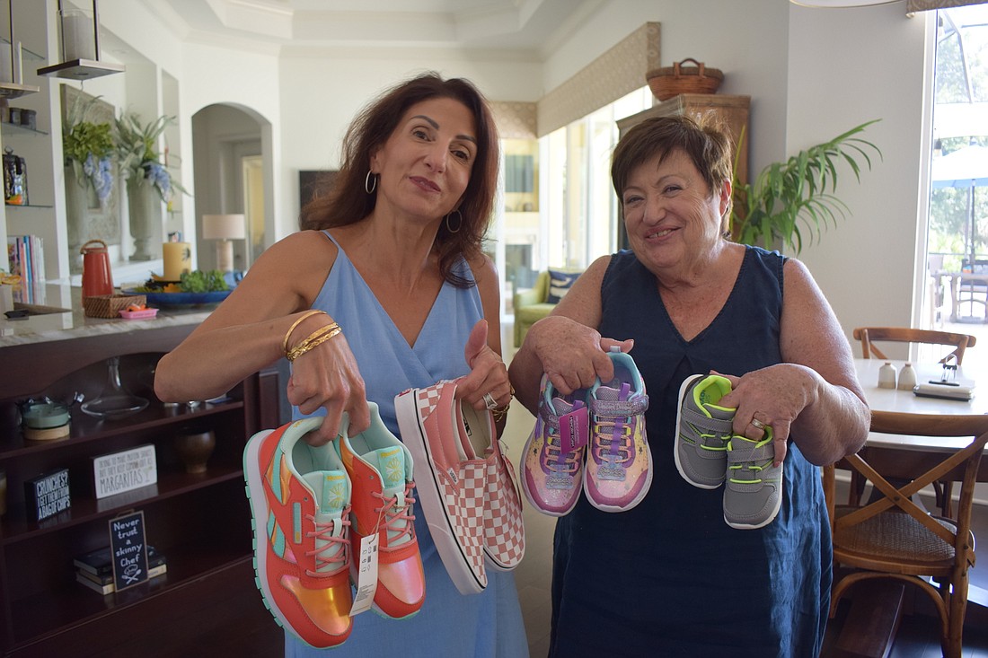 Lake Club Giving Circle founder Barbara Najmy and member Julie Swan show off some of the sneakers the giving circle collected for The Twig nonprofit. (Photo by Jay Heater)