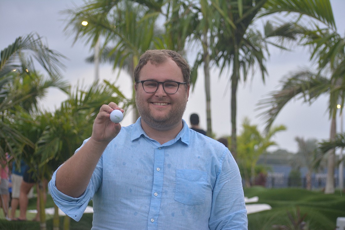 Ryan Kohn holds up the signature Bridgestone golf ball he played with at PopStroke. Each PopStroke golfer gets to keep their ball.