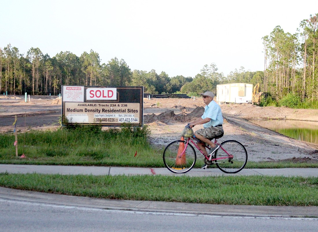 Not far from City Hall, in Town Center, a man rides past a medium density residential development. The city's Building Department is running a surplus in permit fees. Photo by Brian McMillan