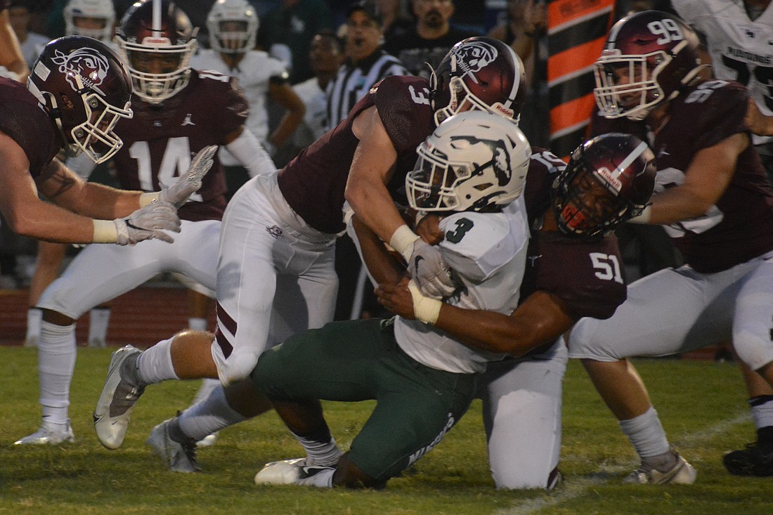 Braden River linebacker Aidan Dangler (3, red) puts a hit on Lakewood Ranch running back Kevin Everhart with teammate Zamarion Mays during the teams&#39; 2021 rivalry game. (File photo)