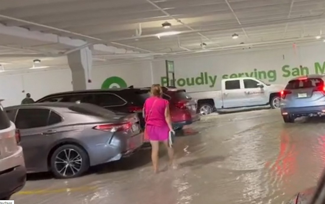 A woman wades through the water in the San Marco Publix parking garage on Aug. 11 in this image from News4Jax.com video.