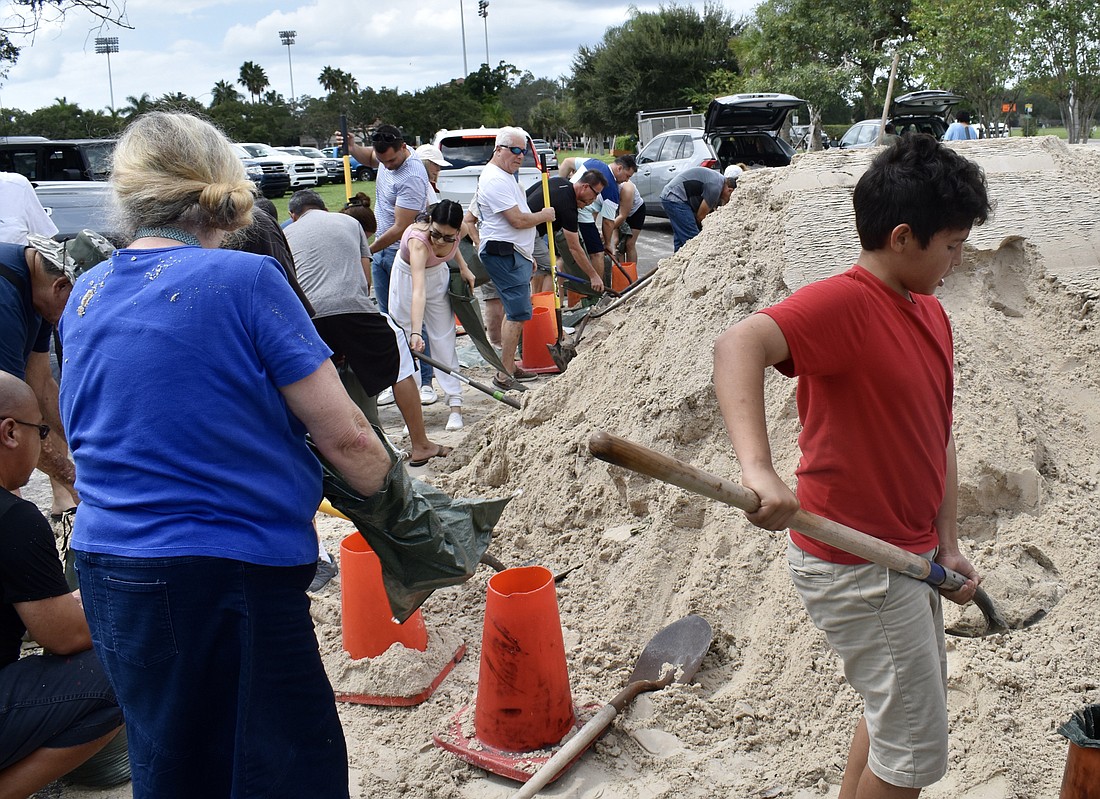 Dozens of people shovel sand into bags at one of three Sarasota County sites for sandbags at Ed Smith Stadium. (Eric Garwood)