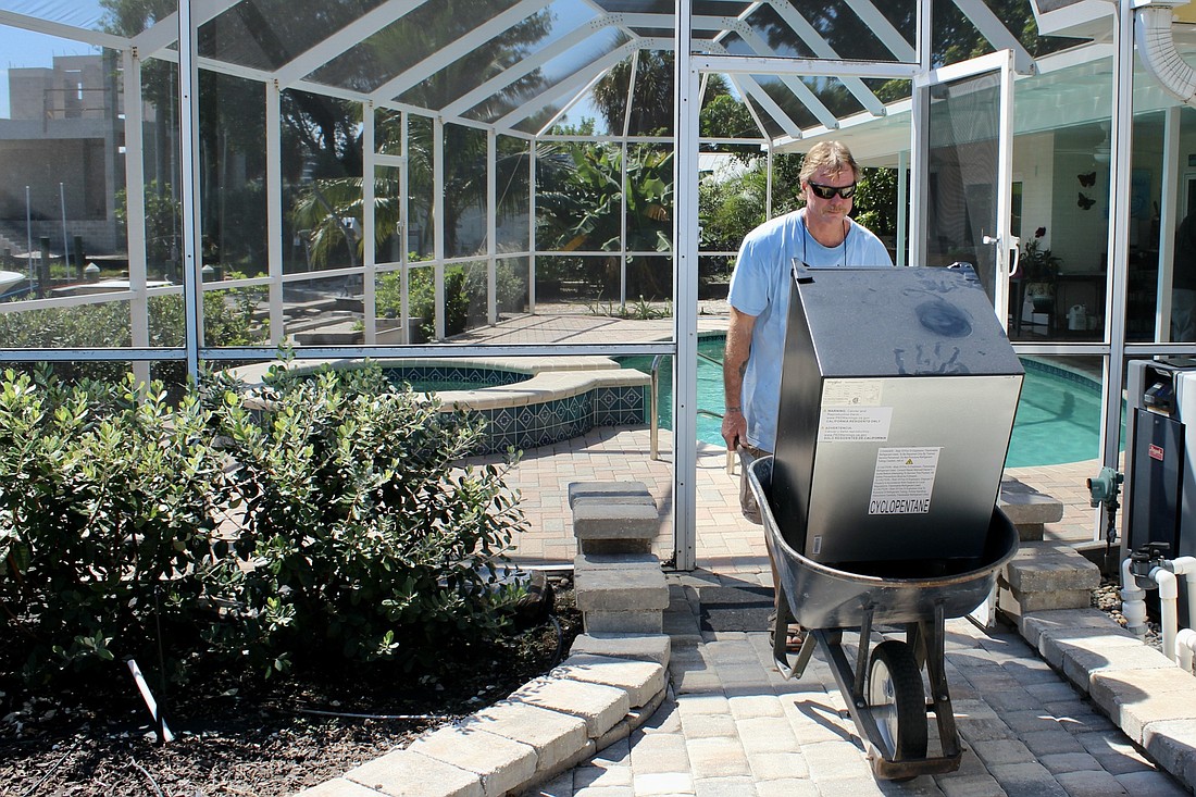 James Keller moves a mini-fridge out of the pool area. All loose items are being moved into the garage. (Lesley Dwyer)