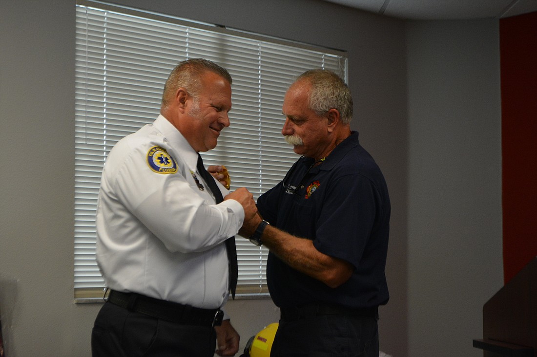 Firefighter-paramedic Jeff Bullock pins new lieutenant Ron Koper&#39;s badge to his uniform. (Photo by Lauren Tronstad)