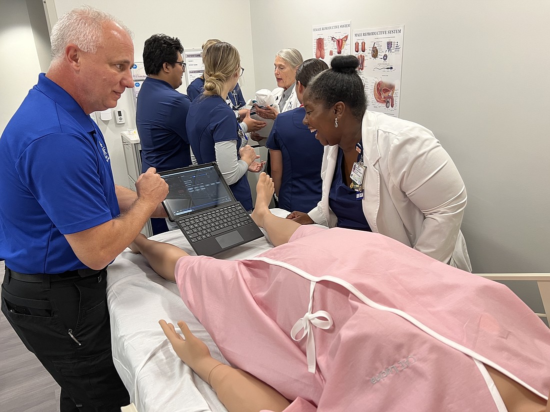 Conrad Dove, director of the simulation center at UNF MedNexus, and instructor Marguerite Richards, a registered nurse, look over the program that allows the robot patient to speak.