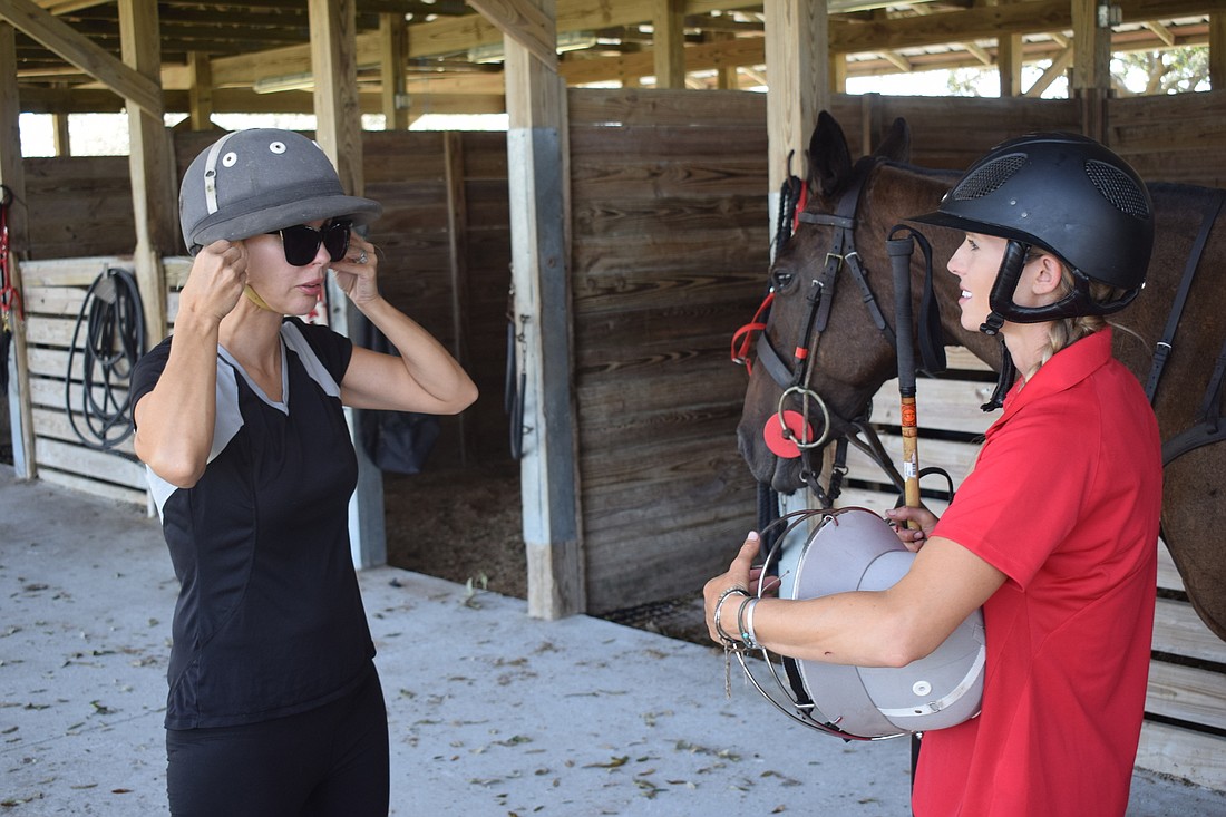 It&#39;s safety first before a polo lesson as Karen Medford tries on helmets for instructor Ashlie Osburg.