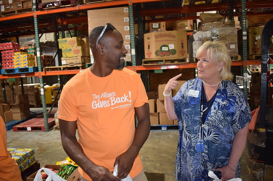 Lakewood Ranch Business Alliance volunteer Patrick Larivaud takes a break from packing food to visit with Meals On Wheels Plus CEO/President Maribeth Phillips.