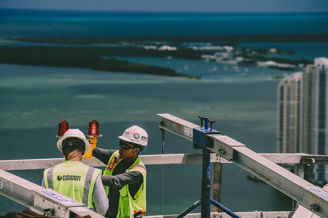 Power Design employees work on the roof of a project in Miami. (Courtesy photo)