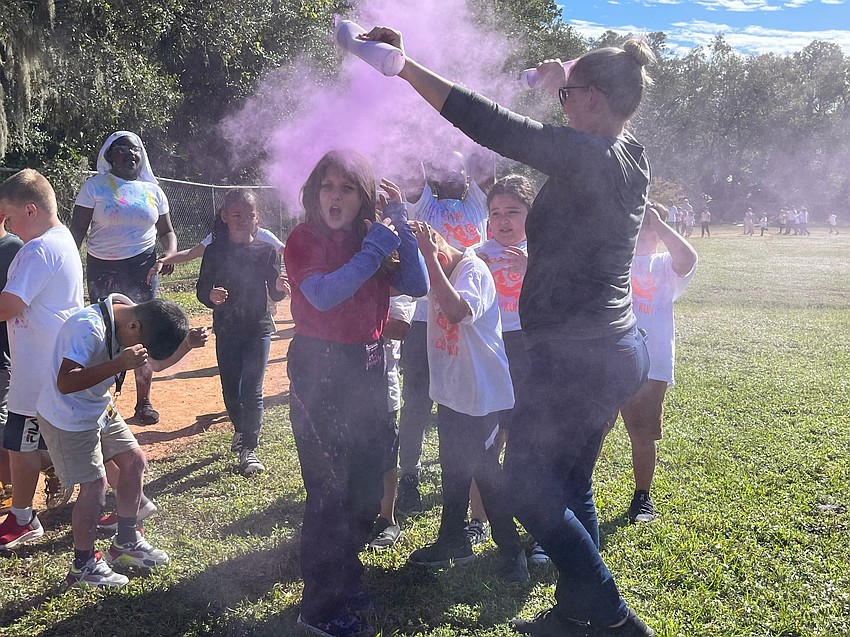 Volunteer Jennifer Farley covers students in purple. 