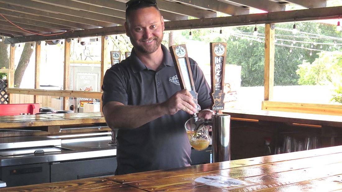 Big Top Brewing co-founder and partner Mike Bisaha draws a beer from a tap at the outdoor bar at its Cock & Bull location on Cattlemen Drive.