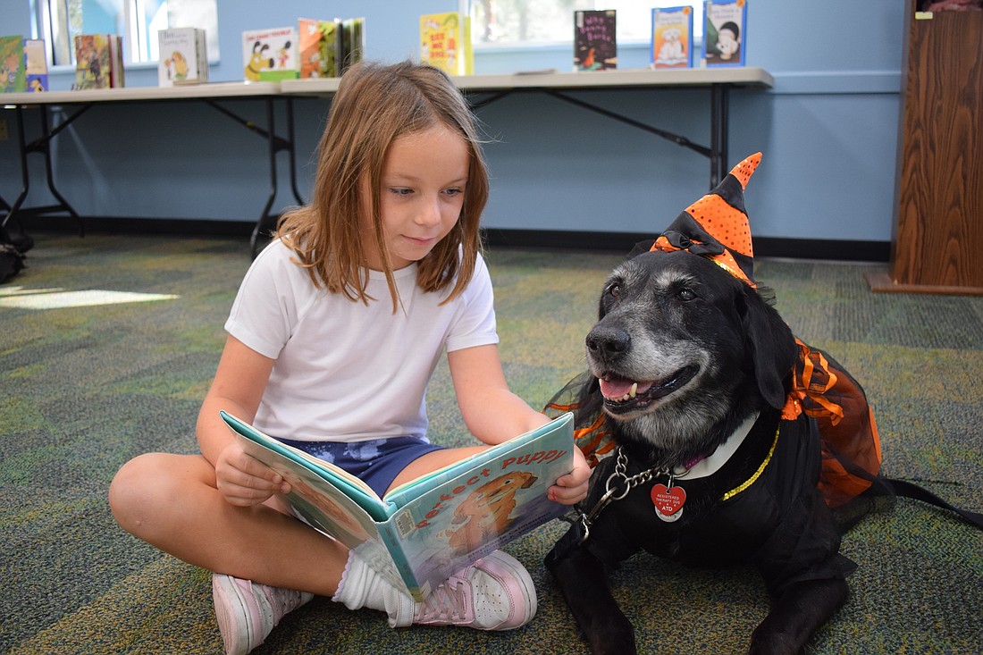 Lakewood Ranch 7-year-old Marissa Mae Famularo reads to 12-year-old Lab mix Annabelle, who was brought to the Braden River Library by Mary Ringland.