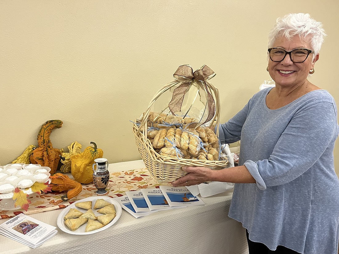 Marilyn Blazakis, the president of the St. Barbara Philoptochos Society, shows off the various pastries and foods available at Autumn Fest. (Photos by Liz Ramos)