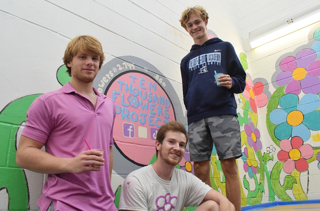 Sophomore Travis Novak works on the mural with artist Tim Gibson and sophomore Collin Dillingham. The Ten Thousand Flowers Project has 2,860 flowers and growing.