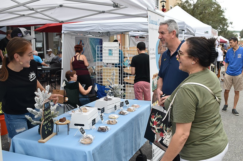 Amanda Duever of Suncoast Cookies describes the cookie offerings to River Club's John and Karen Tagle.