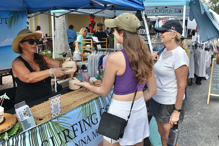Amanda Champ of Surfing Coconut hands a cracked coconut to Alexis Gay who comes from New Jersey and is in attendance alongside her mother, Lakewood Ranch's Dori Gay.