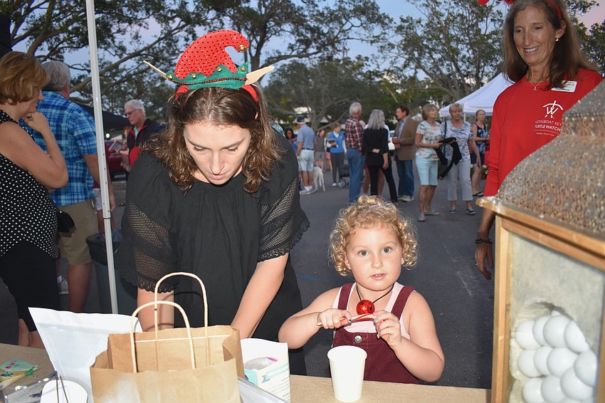 Sienna Cashin fills out a raffle ticket as Cora Cashin grabs a candy cane.