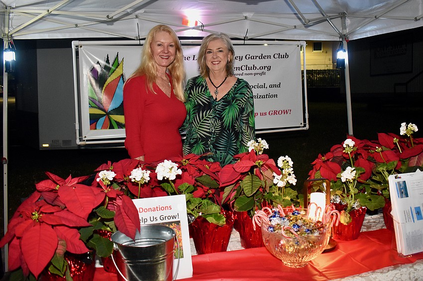 Susan Phillips and Kathleen Wingate give away poinsettas at the Gardening Club booth.