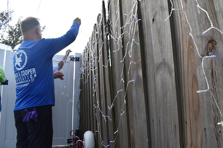 Maverick Johnson and Gary Kortzendorf finish decorating the fence with holiday lights.