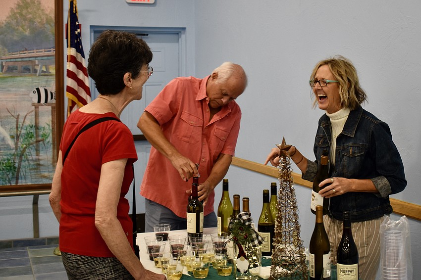 Paula Sharp and Susan Udermann share a laugh, while Dino Sifuentes opens the wine.