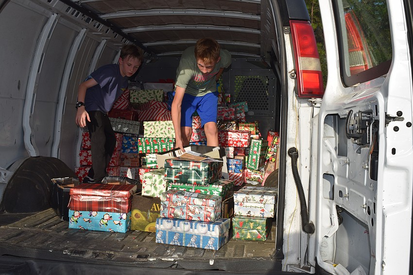 Maddox Towery, 11, and Lou Towery, 13, act as Santa's helpers and organize the shoeboxes in the vans for delivery at the 2022 Shoebox Drive and Reception.