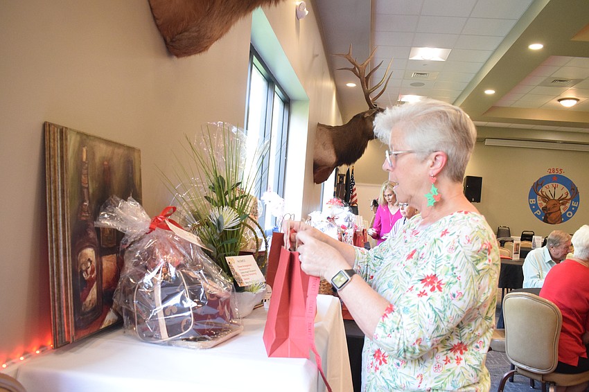 Lakewood Ranch's Lori Valari puts a ticket in a bag in hopes of winning a wine basket. Valari says she comes to the Shoebox Drive and Reception every year. 
