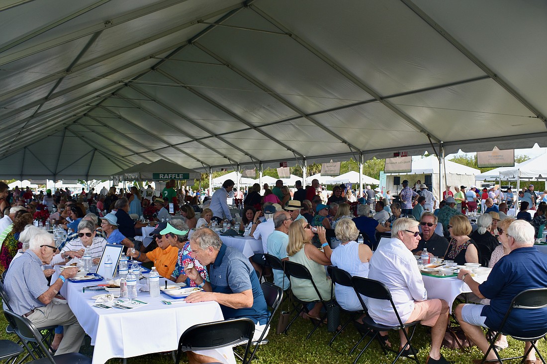 Guests dine under a tent in Ken Thompson Park for the Lawn Party during the 2022 event.