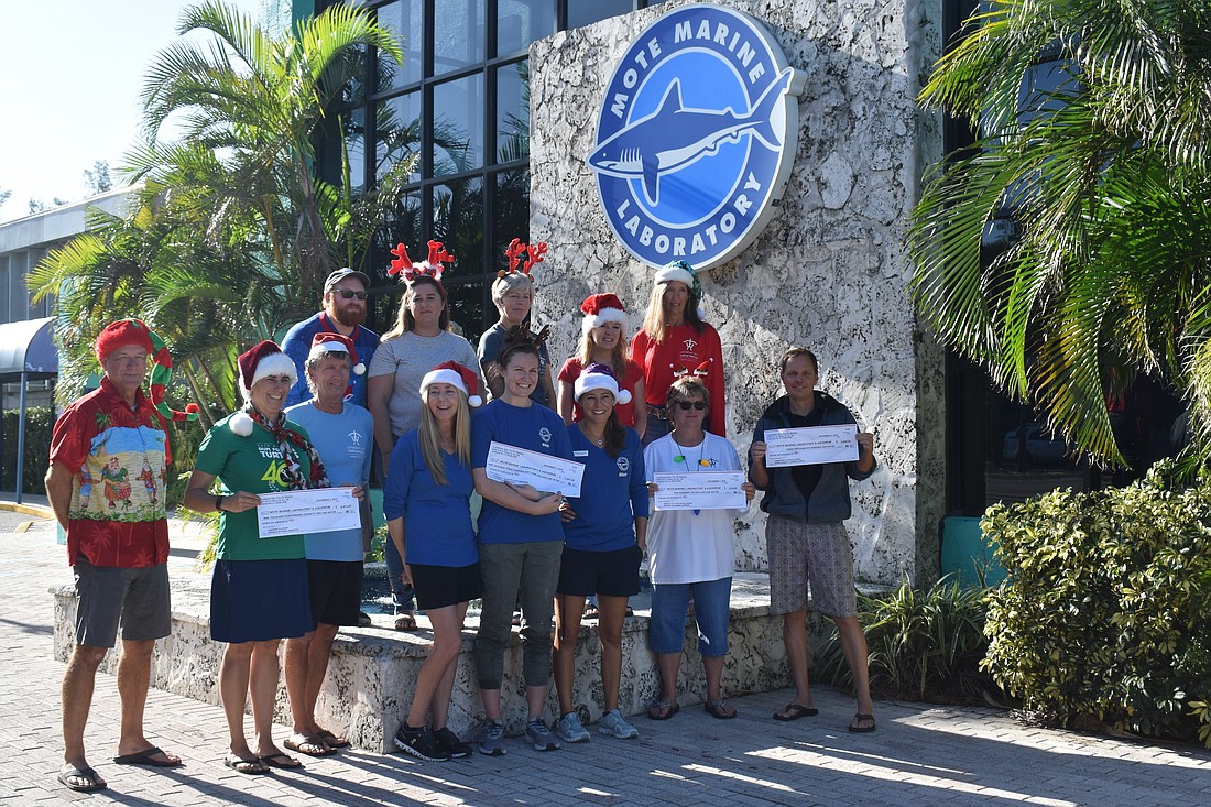 Members of the Longboat Key Turtle Watch deliver donation checks to Mote Marine & Aquarium staff members.