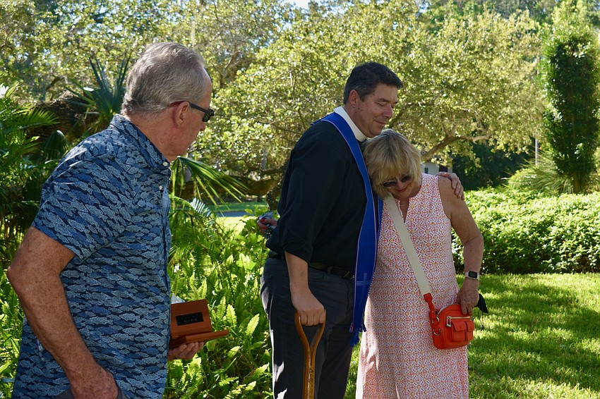 Jeff Vaughn looks on as Rev. David Marshall and Laurel Vaughn embrace after Harvey's ashes are buried.