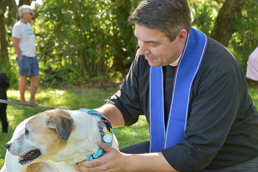 Rev. David Marshall holds blesses Gustie in front of All Angels by the Sea Episcopal Church on Thursday.