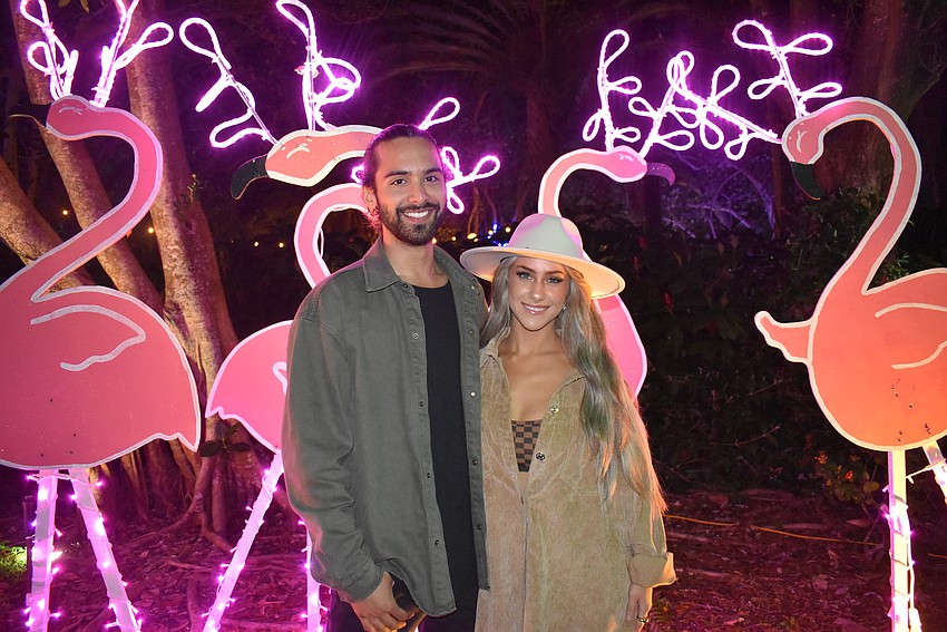 Ryan Helme and Jade Sedacca pose in front of vibrant flamingos.