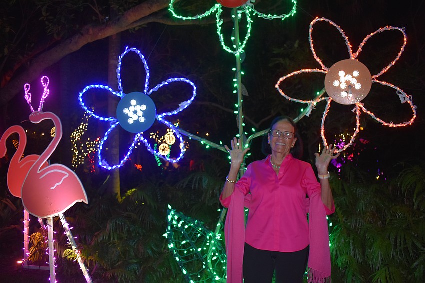 Nancy Port poses in front of vibrant flowers and flamingos.