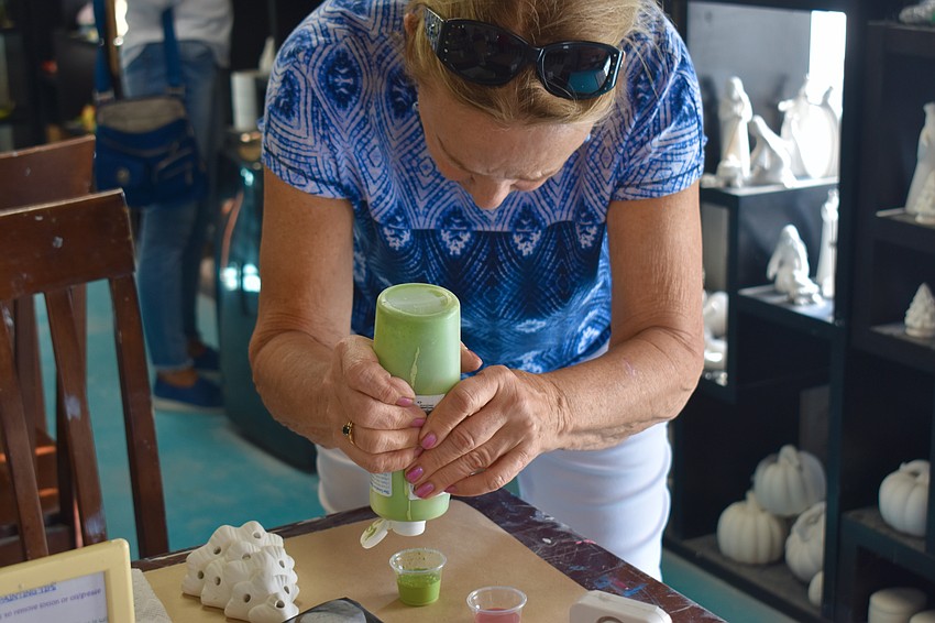 Donna Dolan pours paint for her project.