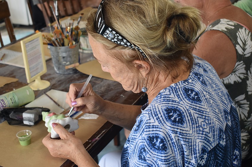 Donna Dolan paints a Christmas tree.