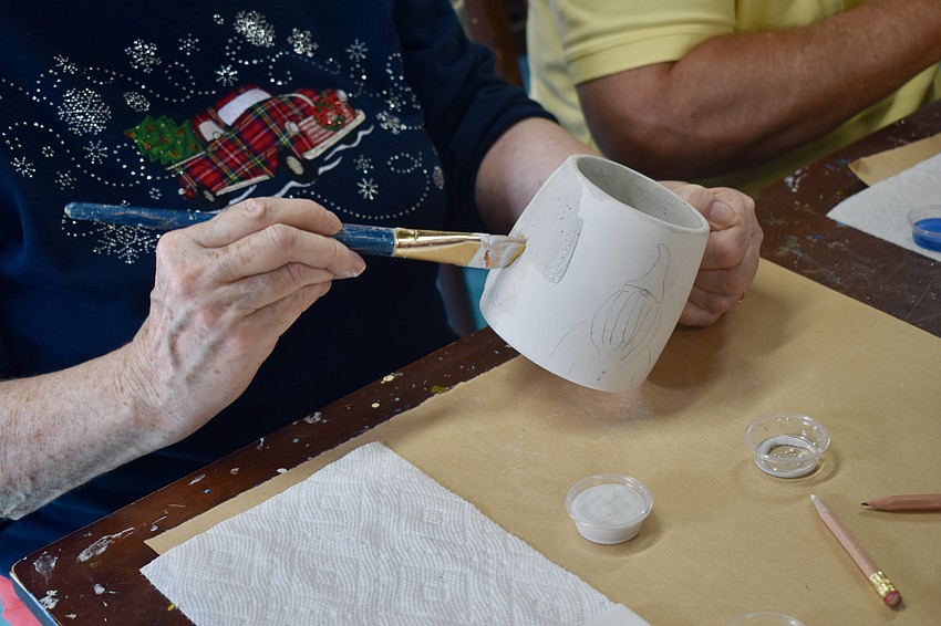 Claire Skerrett paints a mug after penciling a gnome on the side.