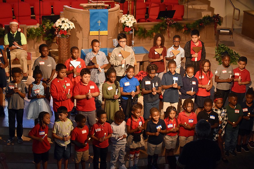 The children hold ring bells and hold candles for thier performance of 