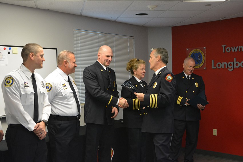 Lt. Tim Haas shakes the hand of Chief Paul Dezzi. Firefighter/paramedic William Lewis, Lt. Ron Koper, Fire Marshal Jane Herrin and Assistant Chief Mike Regnier are on either side.
