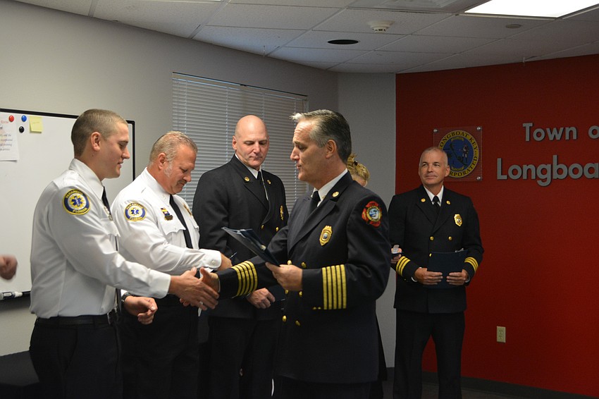 Firefighter/paramedic William Lewis shakes the hand of Chief Paul Dezzi. From left to right: Lt. Ron Koper, Lt. Tim Haas, Assistant Chief Mike Regnier.