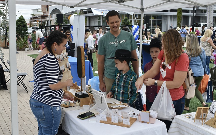 Palmetto's Tim Johnston, 8-year-old Gabe Johnston, 9-year-old Tyler Johnston, and Lynne Johnston visit the Aviella Creations booth by Kristine Vila of Wimauma.