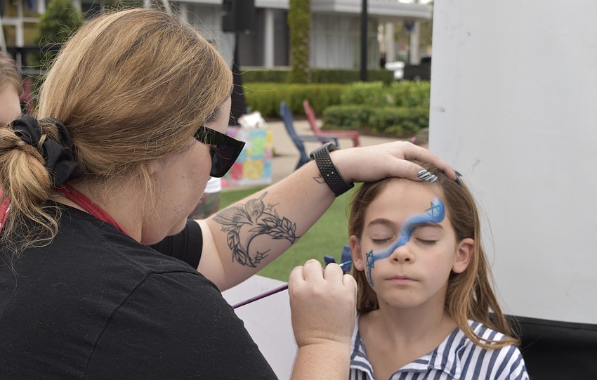 Lakewood Ranch's Cassidy David paints the face of Sarasota's 7-year-old Emily Gordon.