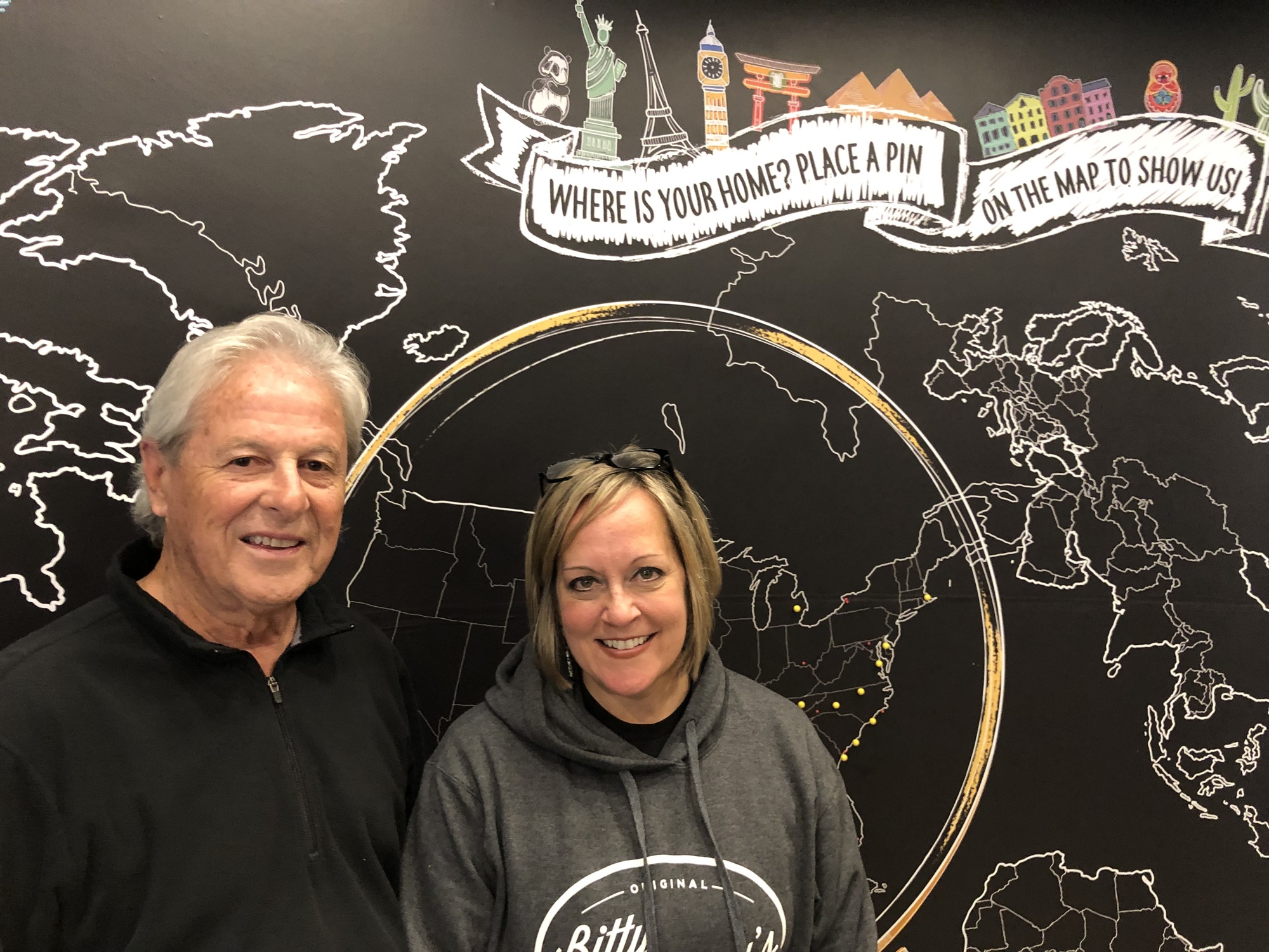 Howard White and Lissie Hurst, owners of the Bitty & Beau’s Coffee franchise location in Jacksonville, stand in front of a map inside the shop that encourages customers to show where they are from.