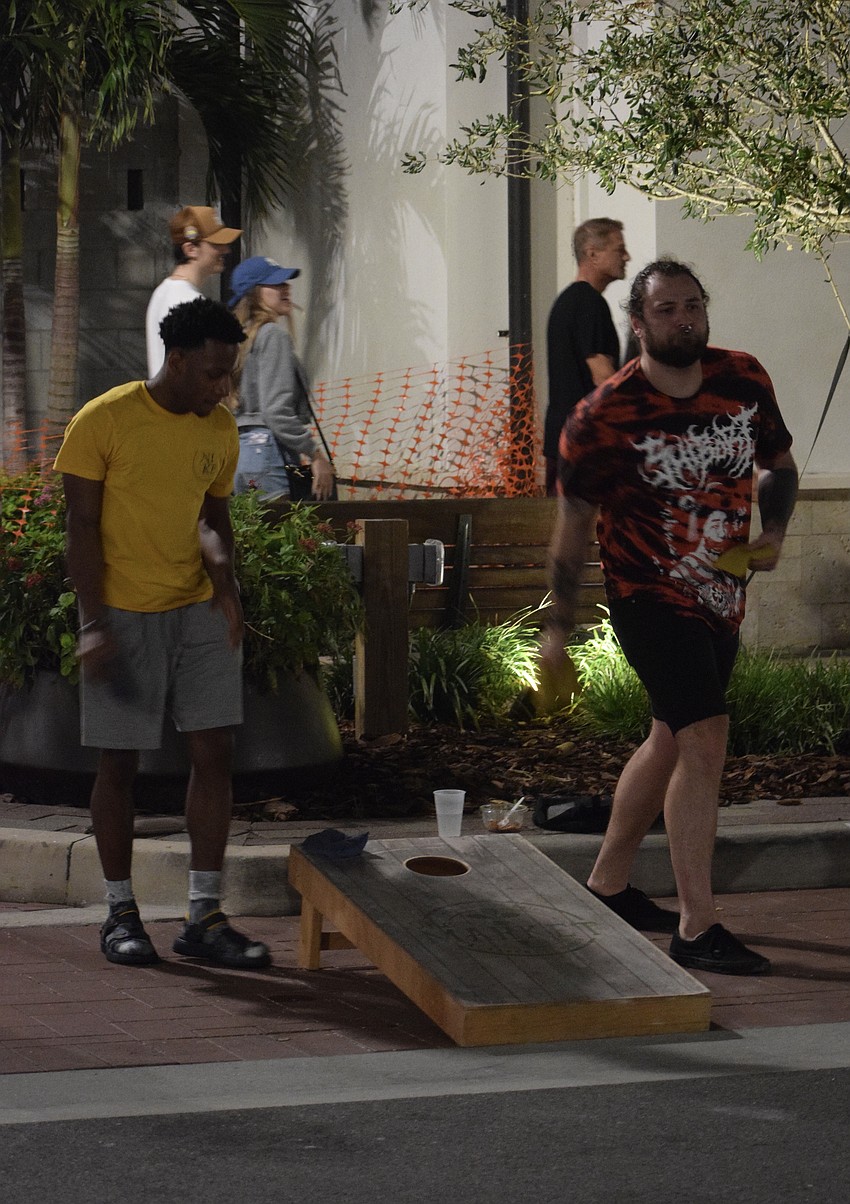Kenyon Campbell and Gunnar Saxon, who are visiting Sarasota from New York, compete in a round of cornhole.