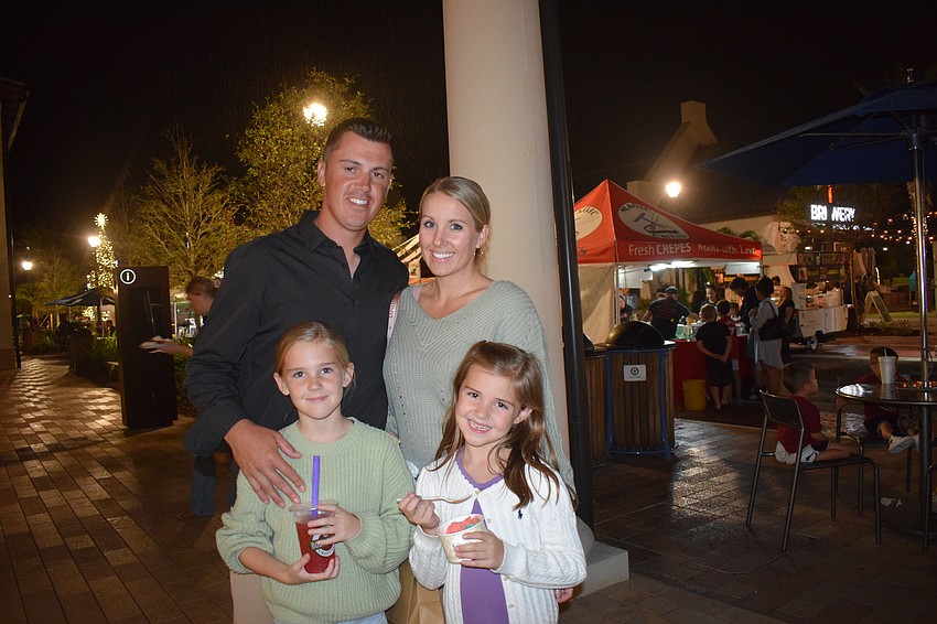 Englewood's Erik Dunigan and his wife, Megan Dunigan, take cover from the rain with their daughters, 9-year-old Lynlee Dunigan, and 7-year-old Laiklyn Dunigan.