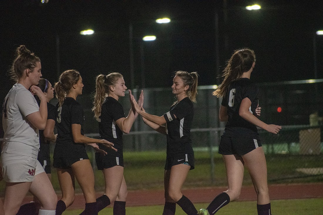 Sophie Lemus gets a high five from Gabrielle Madrid after Lemus scored against Manatee High.