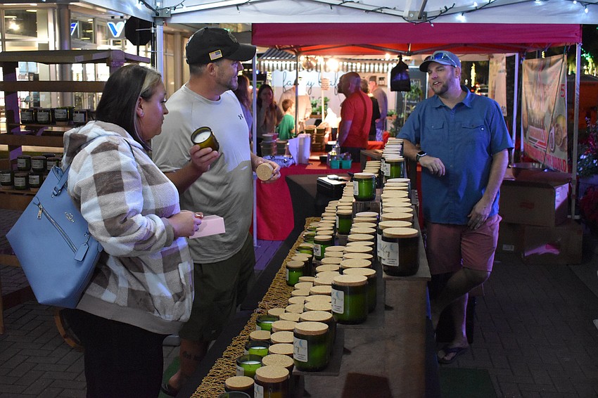 Tara Cowan from Kansas, and Palm Aire's Paul Peays examine the candles at SipNWick with the assistance of Patrick Allen.